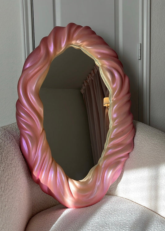 Pink textured mirror on a light-colored surface with a neutral background