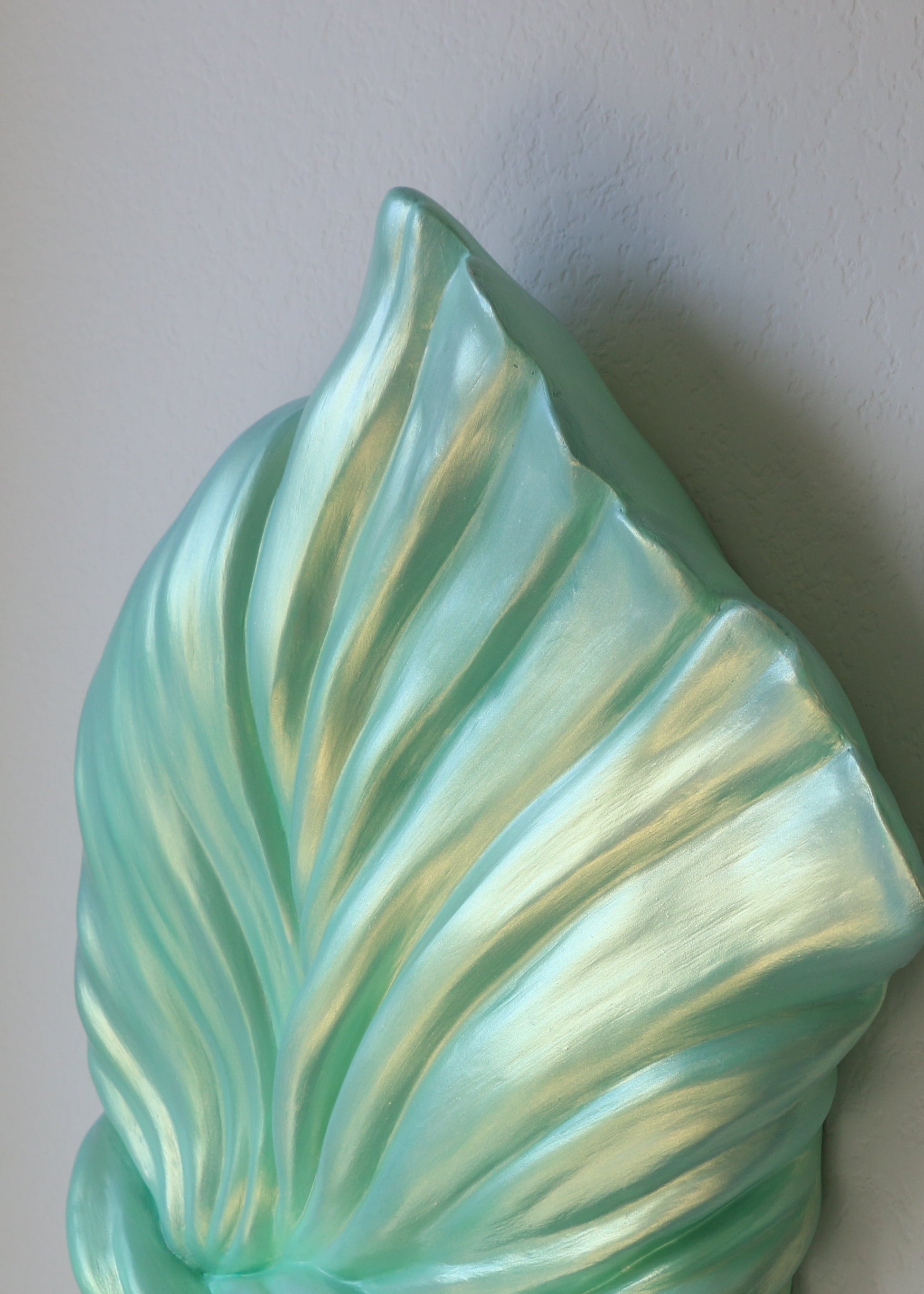 Turquoise ceramic leaf wall art on a plain background